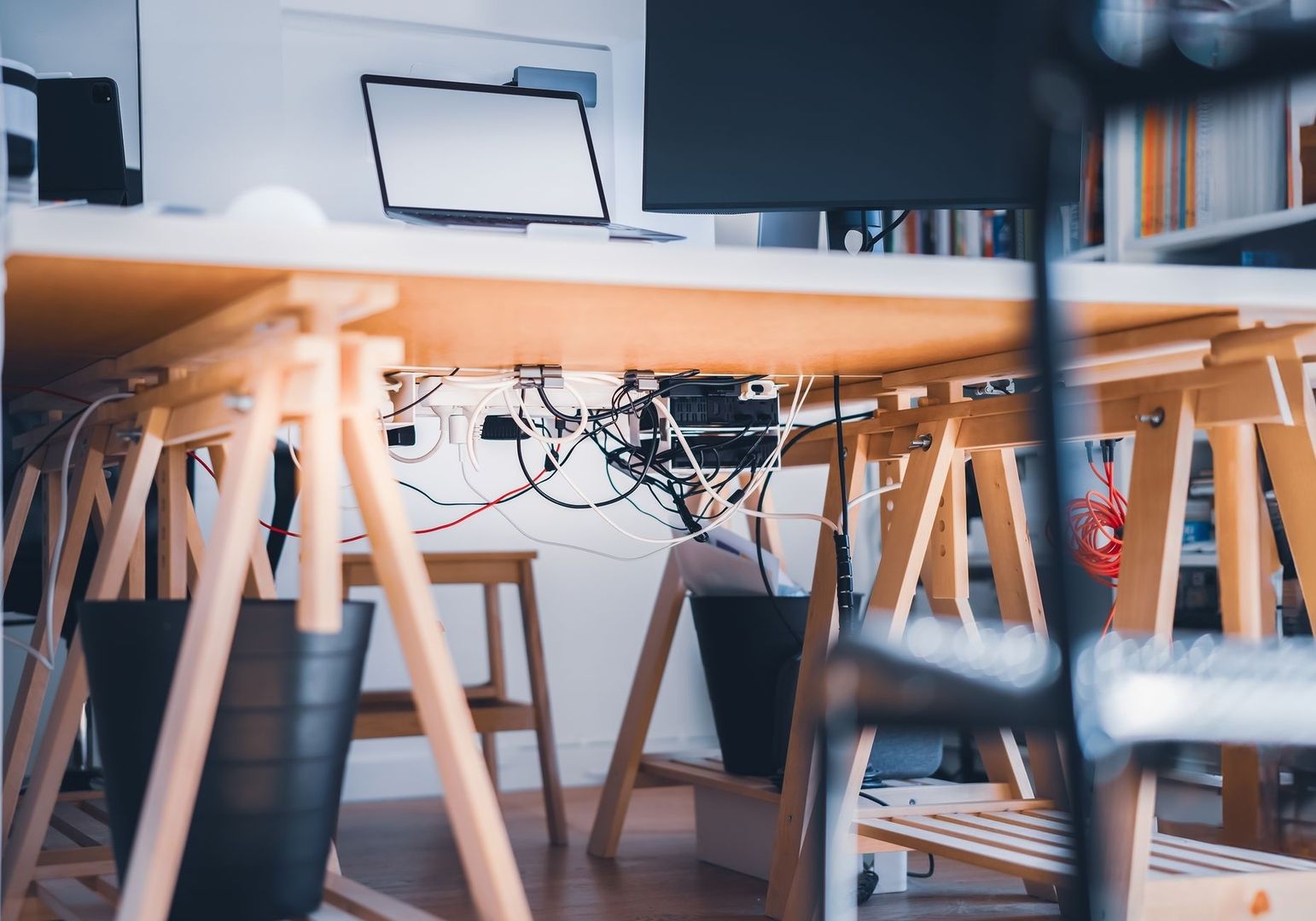 Bureau met monitor, laptop en een wirwar van kabels eronder