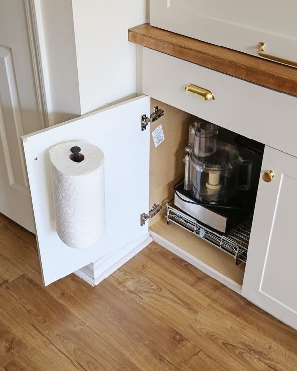 Papierrolhouder aan binnenzijde keukenkastdeur; voedselverwerker in kast. Slimme opbergoplossing.